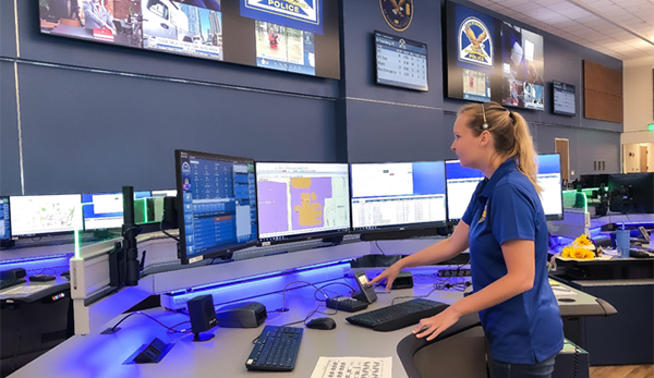 female communications employee standing at her workstation
